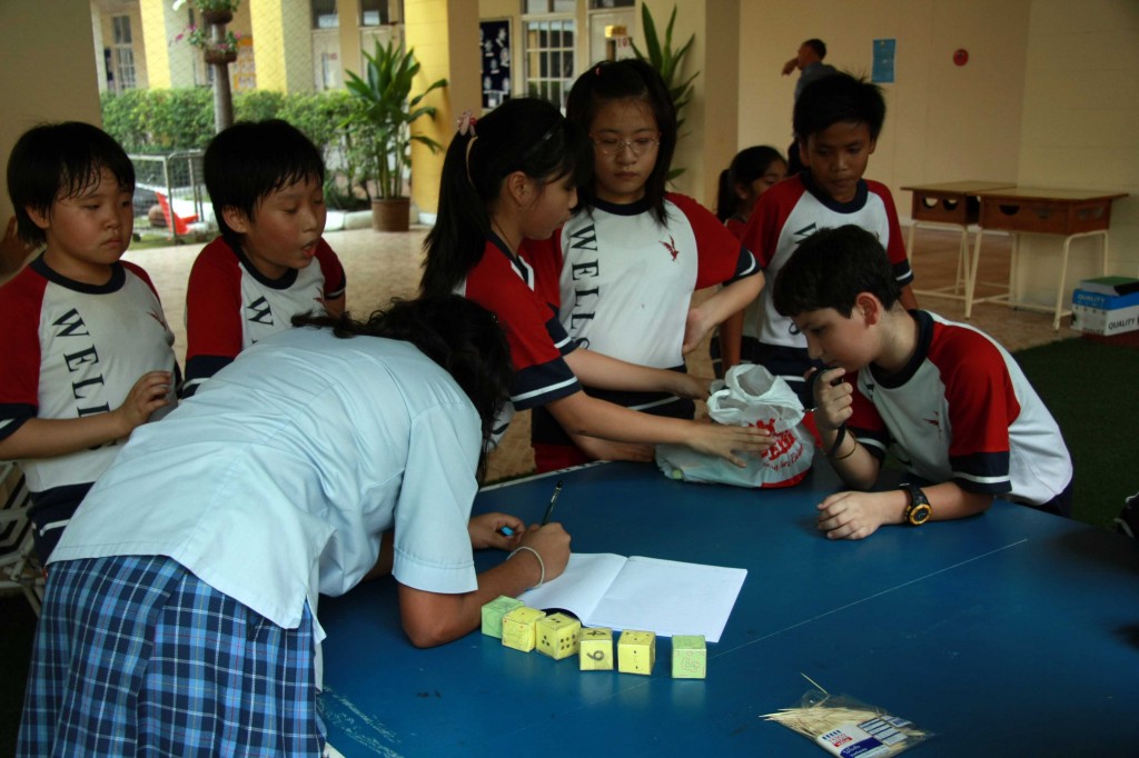 A secondary student playing a game of “Rice Dice Calculation,” organized by Grade 4B students
